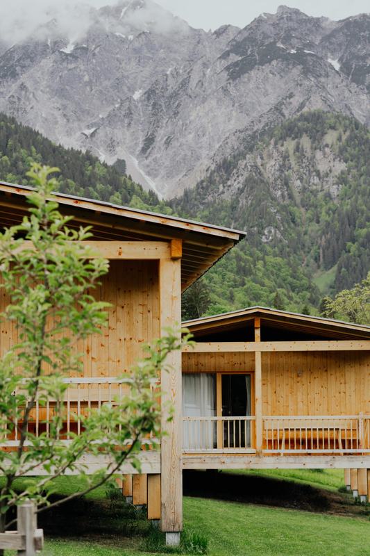 Zwei Chalets im Obstgarten, dahinter der Berg