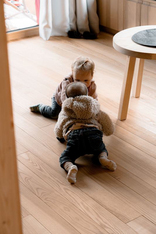 Zwei Kinder spielen auf dem Holzboden
